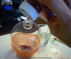 pour glitter into the glass ornament using a homemade paper cone or the container it came in.